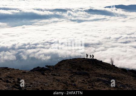 Silhouette escursionista sulla cima del monte Kucelj, sopra la nebbia nella valle di Vipava, Slovenia Foto Stock