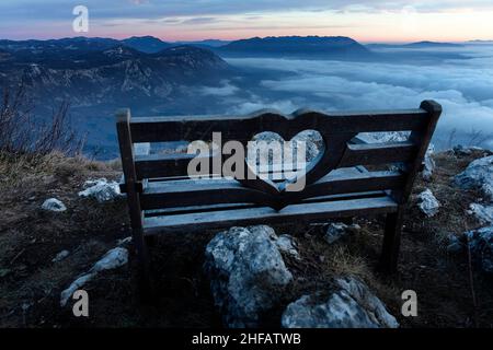 Panchina d'amore e bellissimo panorama verso Nanos sopra la valle Vipava in Slovenia, guardando dalla cima del monte Caven Foto Stock