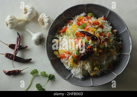 Riso con peperoni saltati. Riso basmati al vapore con peperoni saltati aromatizzati con peperoni rossi e aglio. Scatto su sfondo bianco Foto Stock