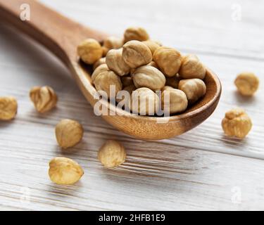 Nocciole sbucciate in un cucchiaio su sfondo bianco di legno Foto Stock