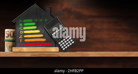 Lavagna a forma di casa con disegno in gesso di una valutazione di efficienza energetica, calcolatore nero e un rotolo di banconote in euro, su un tavolo. Foto Stock