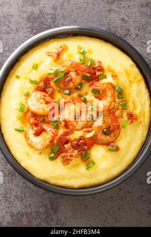 deliziosi gamberi e grits freschi fatti in casa in stile cajun con chioseup cheddar nel piatto sul tavolo di cemento. Vista dall'alto verticale Foto Stock