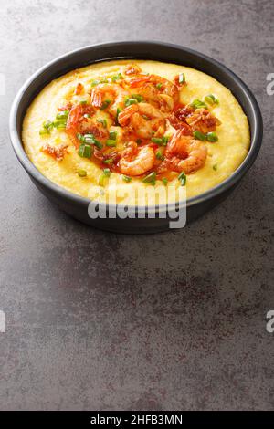 Piatto con freschi e gustosi gamberi e grits primo piano sul tavolo di cemento. Verticale Foto Stock