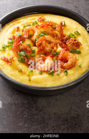 deliziosi gamberi e grits freschi fatti in casa in stile cajun con chioseup cheddar nel piatto sul tavolo di cemento. Verticale Foto Stock