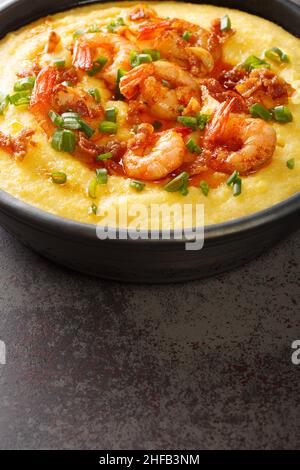 Gamberi fatti in casa e grits con pancetta e Cheddar closeup nel piatto sul tavolo di cemento. Verticale Foto Stock