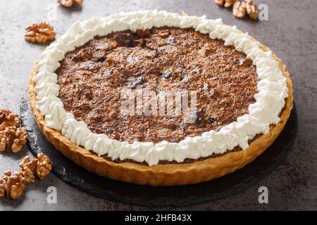 Dessert del Kentucky torta americana di noci di cioccolato con panna montata primo piano in un piatto sul tavolo. Orizzontale Foto Stock