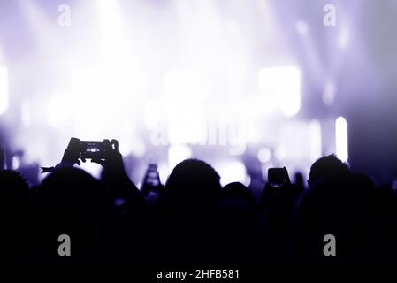 Silhouette di mani la registrazione di un concerto con i telefoni intelligenti. La folla di persone che utilizzano i telefoni intelligenti per fotografare un concerto Foto Stock