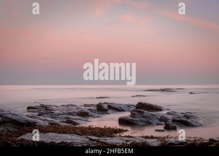 Tramonto su Browns Bay, Whitley Bay con la luna nel cielo Foto Stock