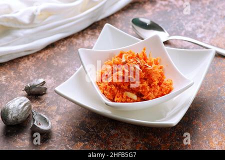 Indian Food Gajar ka Halwa (Carrot Sweet Pudding) in una ciotola bianca con un cucchiaio Foto Stock