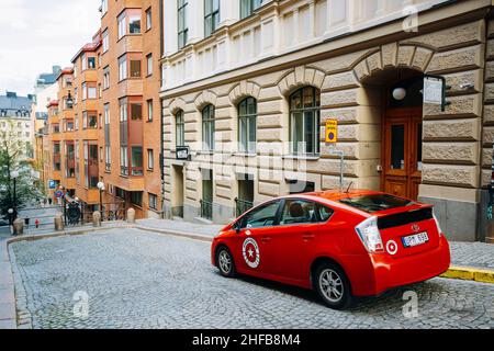 Auto rossa Toyota Prius parcheggiata al marciapiede sulla via David Bagares Stoccolma, Svezia Foto Stock