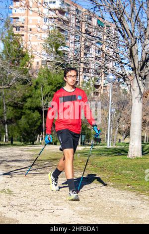 Nordic walking. Giovane che pratica lo sport nordic walking con le racchette in un parco all'aperto a Madrid, in Spagna. Europa. Fotografia. Foto Stock