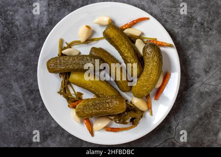 Cetrioli sottaceto su sfondo scuro. Primo piano dei cetrioli sottaceto in un piatto di ceramica. Primo piano. Vista dall'alto Foto Stock