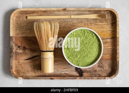 Polvere verde di tè Matcha e sussurro di bambù in un vassoio di legno primo piano. Cerimonia del tè giapponese. Bevanda organica sana. Vista dall'alto. Foto Stock