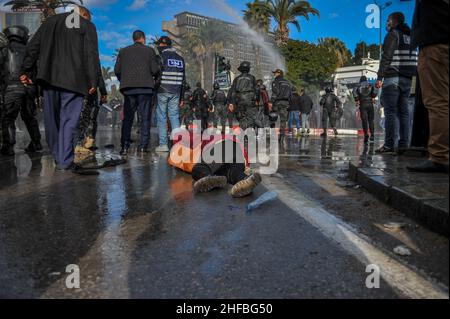 Tunisi, Tunisia. 14th Jan 2022. Tunisi, Tunisia. 14 gennaio 2022. I manifestanti si radunano contro il presidente Kais Saied in occasione del 10th° anniversario della rivoluzione del 2011. I manifestanti hanno sfidato il divieto di raduni e manifestazioni imposto per affrontare un forte aumento delle infezioni da Coronavirus, per esprimere il loro dissenso contro la sospensione del parlamento da parte del Presidente tunisino Kais Saied nel luglio 2021. I manifestanti hanno dovuto affrontare un pesante dispiegamento di forze di sicurezza, che hanno utilizzato cannoni ad acqua per disperderli (Credit Image: © Hasan Mrad/IMAGESLIVE via ZUMA Press Wire) Foto Stock