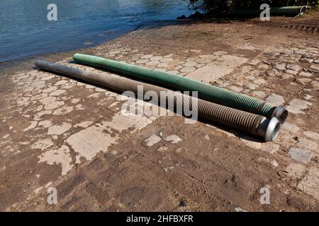 tubi flessibili per lo smaltimento del concime liquido nel fiume Foto Stock