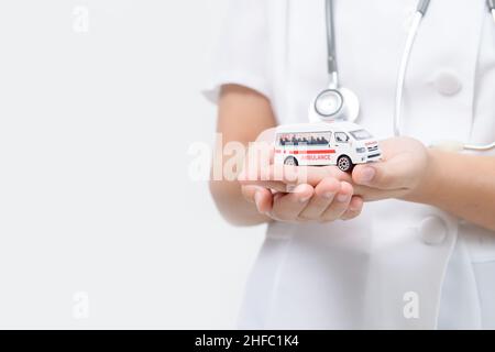 Modello di ambulanza in mano del medico isolato su sfondo bianco, servizio di trasferimento del paziente o concetto di assicurazione Foto Stock