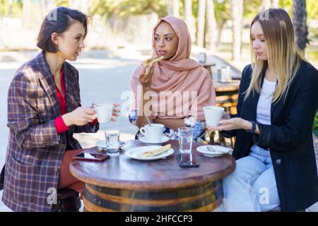 Giovani donne diverse bere caffè in strada caffè Foto Stock