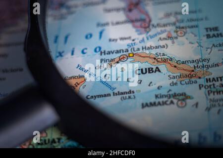 Cuba su una mappa del mondo attraverso una lente d'ingrandimento. Pianificazione delle destinazioni di viaggio cubane bloccato Foto Stock