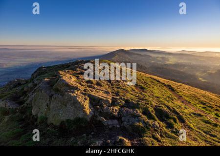 Rocce di granito illuminate dal sole a Worcestershire Beacon nel pomeriggio invernale a Malverns, Inghilterra Foto Stock