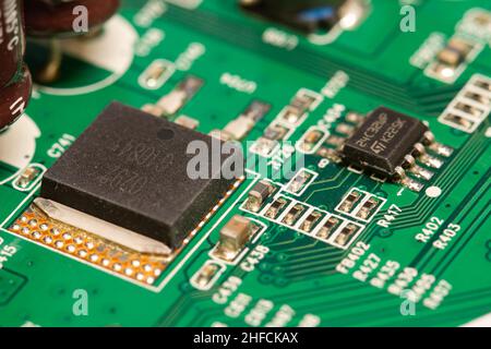 Molti piccoli componenti elettronici saldati su una scheda a circuito stampato (PCB) verde. Foto Stock