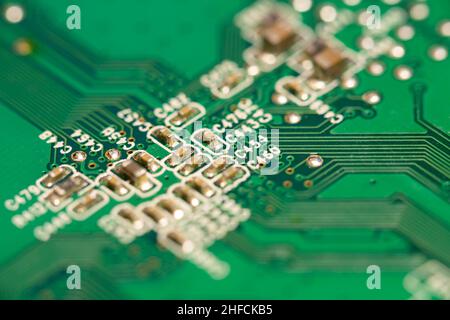 Molti piccoli componenti elettronici saldati su una scheda a circuito stampato (PCB) verde. Foto Stock