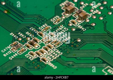 Molti piccoli componenti elettronici saldati su una scheda a circuito stampato (PCB) verde. Foto Stock