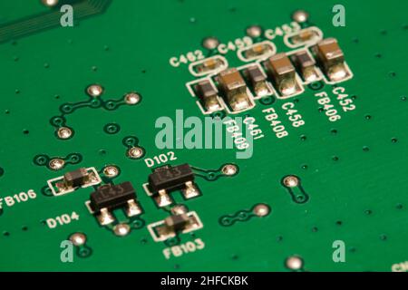 Molti piccoli componenti elettronici saldati su una scheda a circuito stampato (PCB) verde. Foto Stock