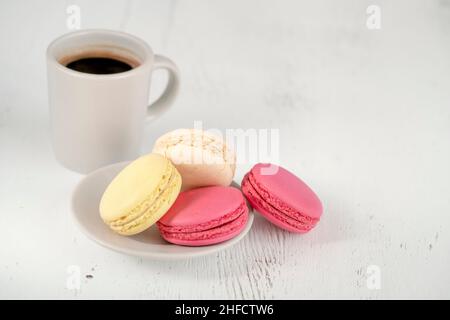 macaroon e caffè, macaroon colorati e tazza di caffè su tavola di legno. deliziosi biscotti francesi su sfondo di legno Foto Stock