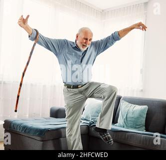 Ritratto di un uomo anziano attivo con un bastone di canna che balla a casa Foto Stock