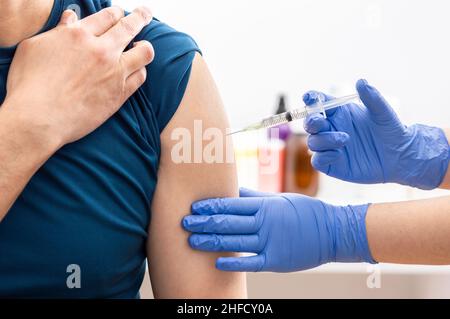 Shot di un'infermiera che applica un vaccino al braccio del paziente contro il covid 19 Foto Stock