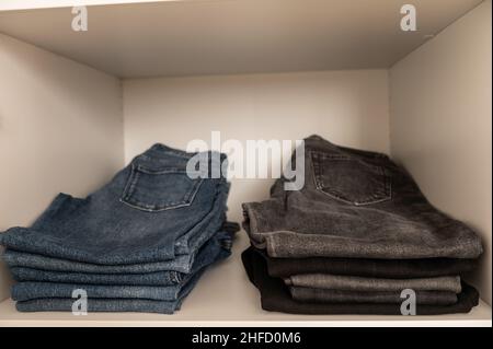 Primo piano di foto di un mucchio di jeans blu perfettamente ripiegati su scaffale in guardaroba Foto Stock