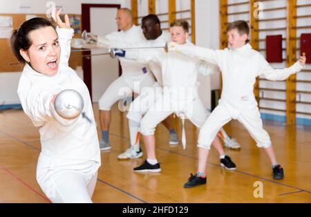 Giovane fencer donna che pratica efficaci tecniche di scherma in aula di formazione Foto Stock