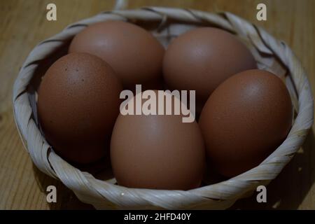 Far rosolare le uova di pollo in un cestino di foglie di palma su un rustico tavolo di legno Foto Stock