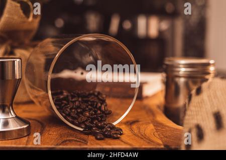 I chicchi di caffè si versano sul pannello di legno Foto Stock