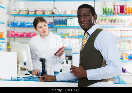 Ritratto di sorridente cliente maschile afroamericano acquistare farmaci in farmacia moderna Foto Stock