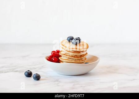 Stack di farina di grano saraceno senza glutine frittelle decorate con mirtillo e ribes rosso, simbolo del Martedì Shrove, fuoco selettivo Foto Stock