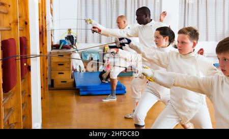 Gruppo che pratica le tecniche di scherma in palestra Foto Stock