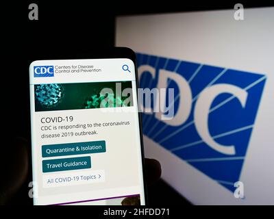 Persona che tiene lo smartphone con il sito Web dei Centri per il controllo e la prevenzione delle malattie (CDC) sullo schermo con il logo. Concentrarsi sul centro del display del telefono. Foto Stock