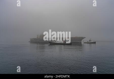 BREMERTON, WA (15 gennaio 2022) i rimorchiatori navali supportano il traino dell'ex USS Kitty Hawk nel suo transito finale dalla base navale Kitsap – Bremerton, Washington, 15 gennaio 2022, ad un impianto di demolizione navale di Brownsville, Texas. Kitty Hawk, l’ultima portaerei a propulsione convenzionale commissionata dalla Marina, operò per 48 anni prima che fosse smantellata nel 2009. Come altri vettori aerei della Marina da quando USS Langley è stato commissionato 100 anni fa, Kitty Hawk e il resto dei vettori aerei della nostra nazione e le ali aeree imbarcate hanno proiettato potenza, un controllo del mare sostenuto, una deterrenza rafforzata, Foto Stock