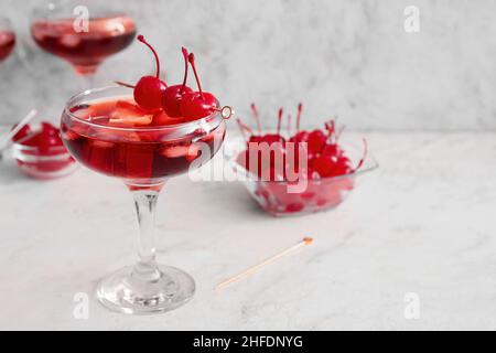 Bicchiere di cocktail Manhattan ghiacciato con ciliegie su sfondo chiaro Foto Stock