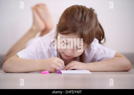 La bambina si trova sul pavimento e si disegna Foto Stock