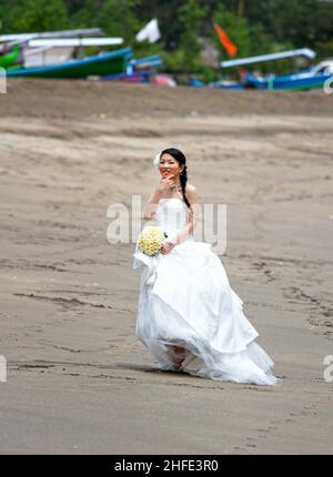 Una sposa asiatica che ha fotografie pre-matrimonio scattate a Tuban Beach, Bali in Indonesia. Foto Stock