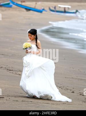 Una sposa asiatica che ha fotografie pre-matrimonio scattate a Tuban Beach, Bali in Indonesia. Foto Stock