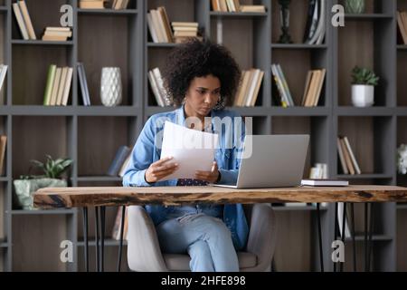 Focalizzata millenaria Afro American imprenditore ragazza fare lavoro di carta al portatile Foto Stock