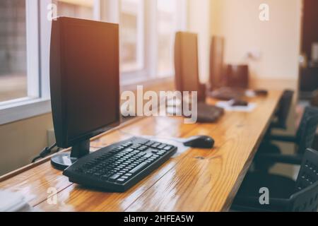 fila di computer desktop sul banco bar in legno per il servizio internet in internet cafe Foto Stock