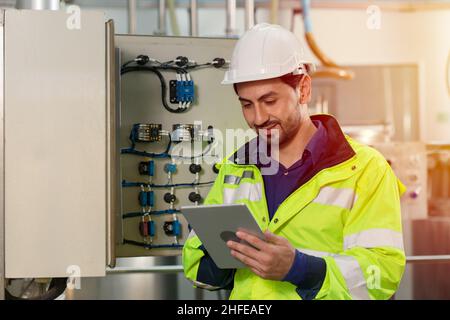 tecnico che lavora controllando la scatola fusibili elettrica di manutenzione e la linea di alimentazione in fabbrica. Foto Stock