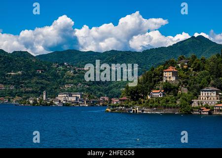 Parte di Orta San Giulio e l'isola di San Giulio vista attraverso il Lago d'Orta, montagne circostanti in lontananza. Foto Stock