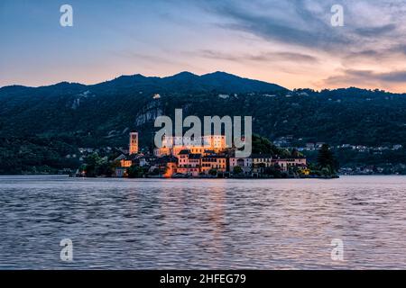 Isola di San Giulio con Basilica di San Giulio vista sul Lago d'Orta, montagne circostanti in lontananza, al tramonto. Foto Stock