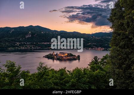 Veduta aerea dal Sacro Monte sull'Isola di San Giulio con la Basilica di San Giulio al centro del Lago d'Orta, al tramonto Foto Stock