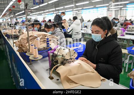 (220116) -- YUTIAN, 16 gennaio 2022 (Xinhua) -- i lavoratori sono visti in un laboratorio della base di produzione di Erke nel parco industriale di Tianjin nella contea di Yutian, nella regione autonoma Xinjiang Uygur della Cina nord-occidentale, 14 gennaio 2022. La Contea di Yutian, un tempo un'area colpita dalla povertà nello Xinjiang, ha intensificato lo sviluppo di industrie ad alta intensità di manodopera, tra cui tessile, abbigliamento e calzetteria. Nel parco industriale di Tianjin a Yutian, una base di produzione del marchio sportivo cinese Erke è stata messa in funzione il 1 gennaio 2022, offrendo più di 500 posti di lavoro per la gente del posto. Maynurhan Amang e suo marito Abusulezizi ma Foto Stock